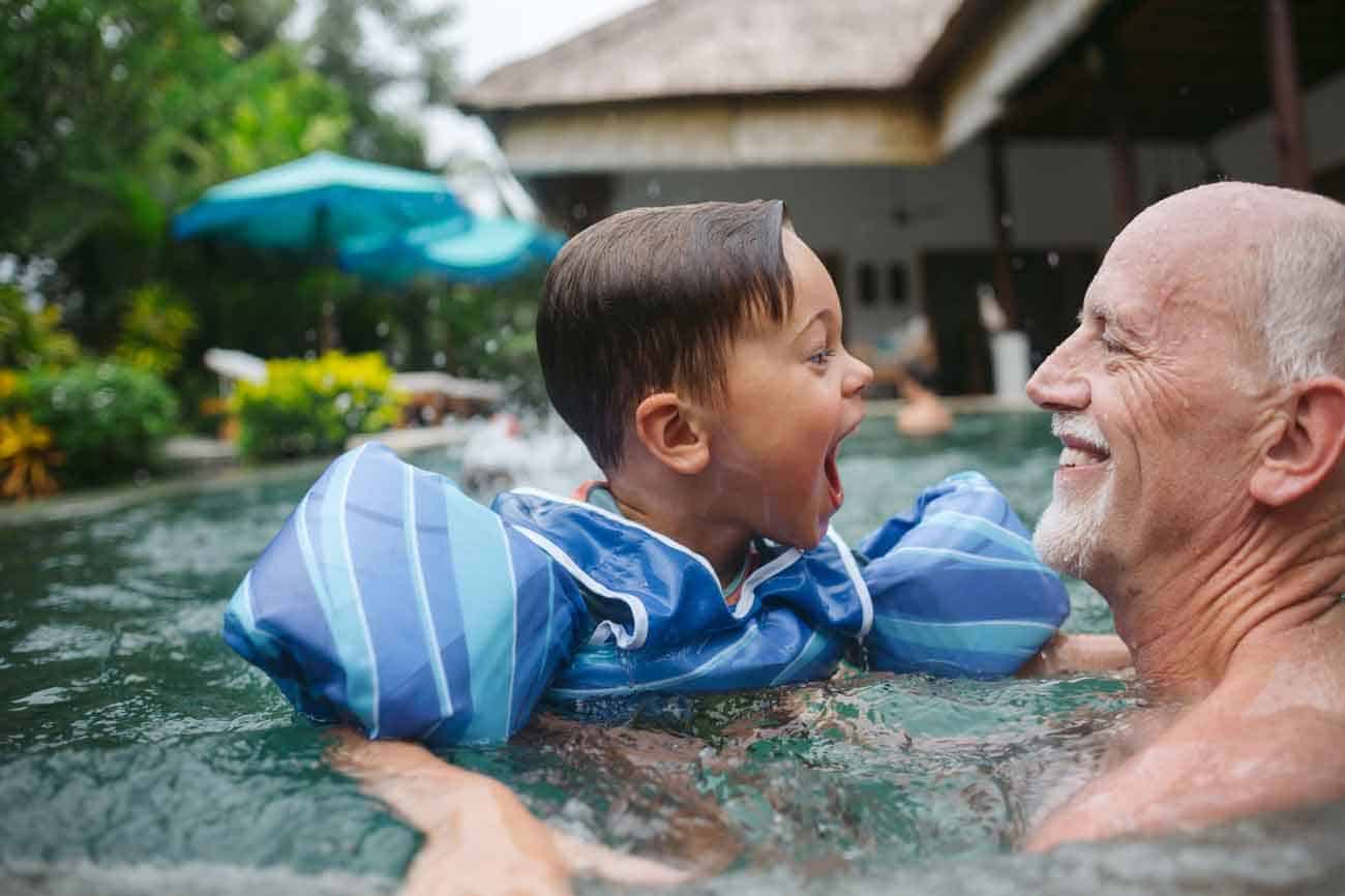 Happy, energetic grandpa playing with grandchild in outdoor pool