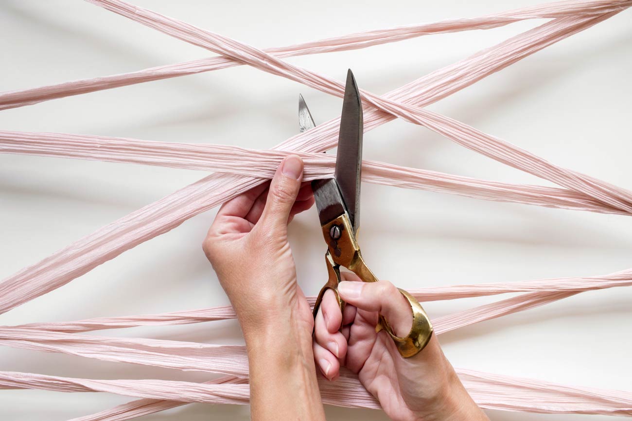 hands using scissors to cut a tangle of silk ribbon