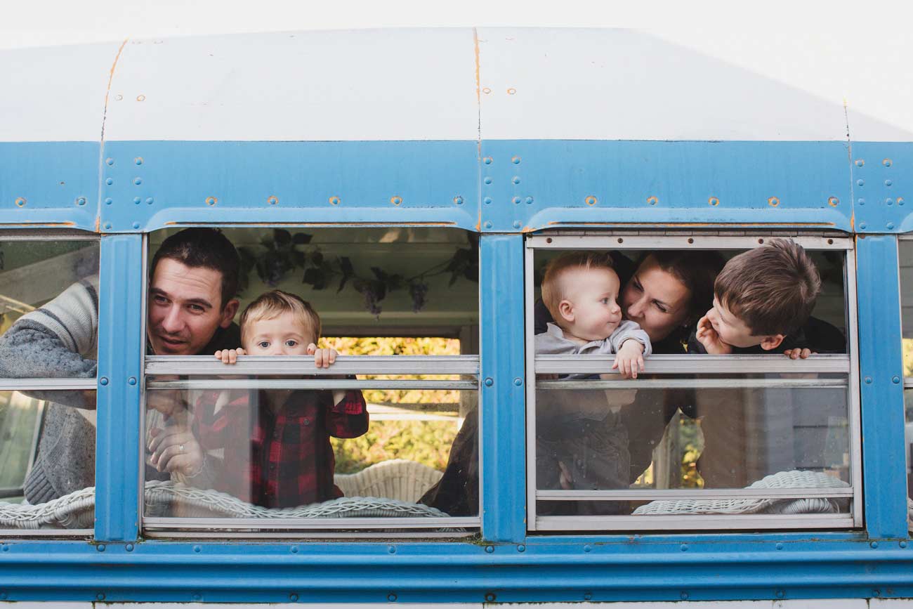 Young family of five looking out bus window