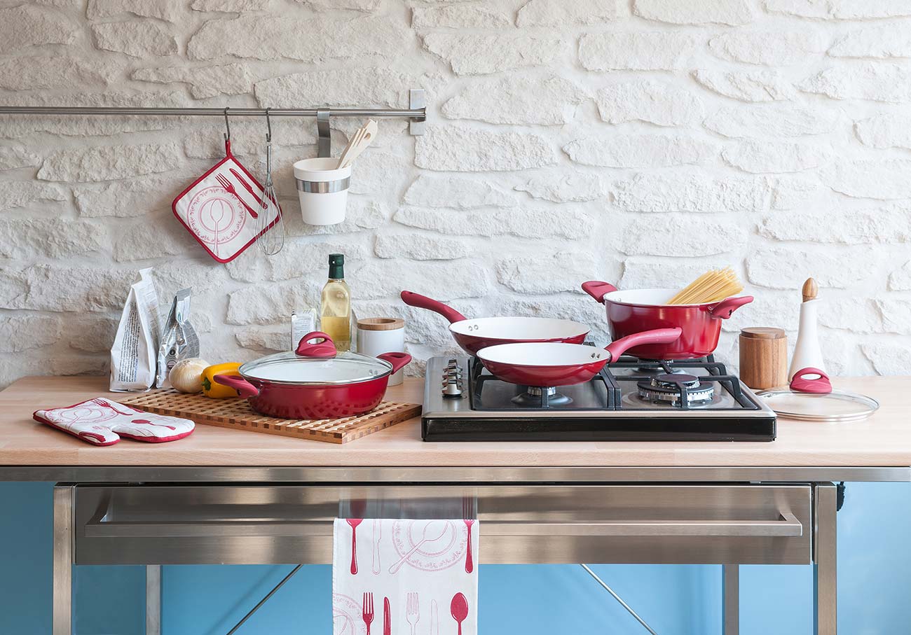 Modern red kitchen behind brick wall with red cookware set