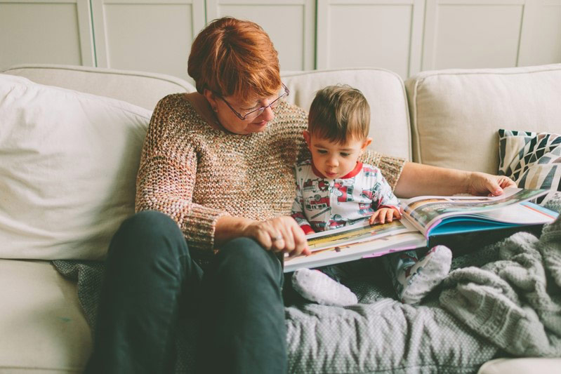 Grandmother and young grandchild reading together on the couch