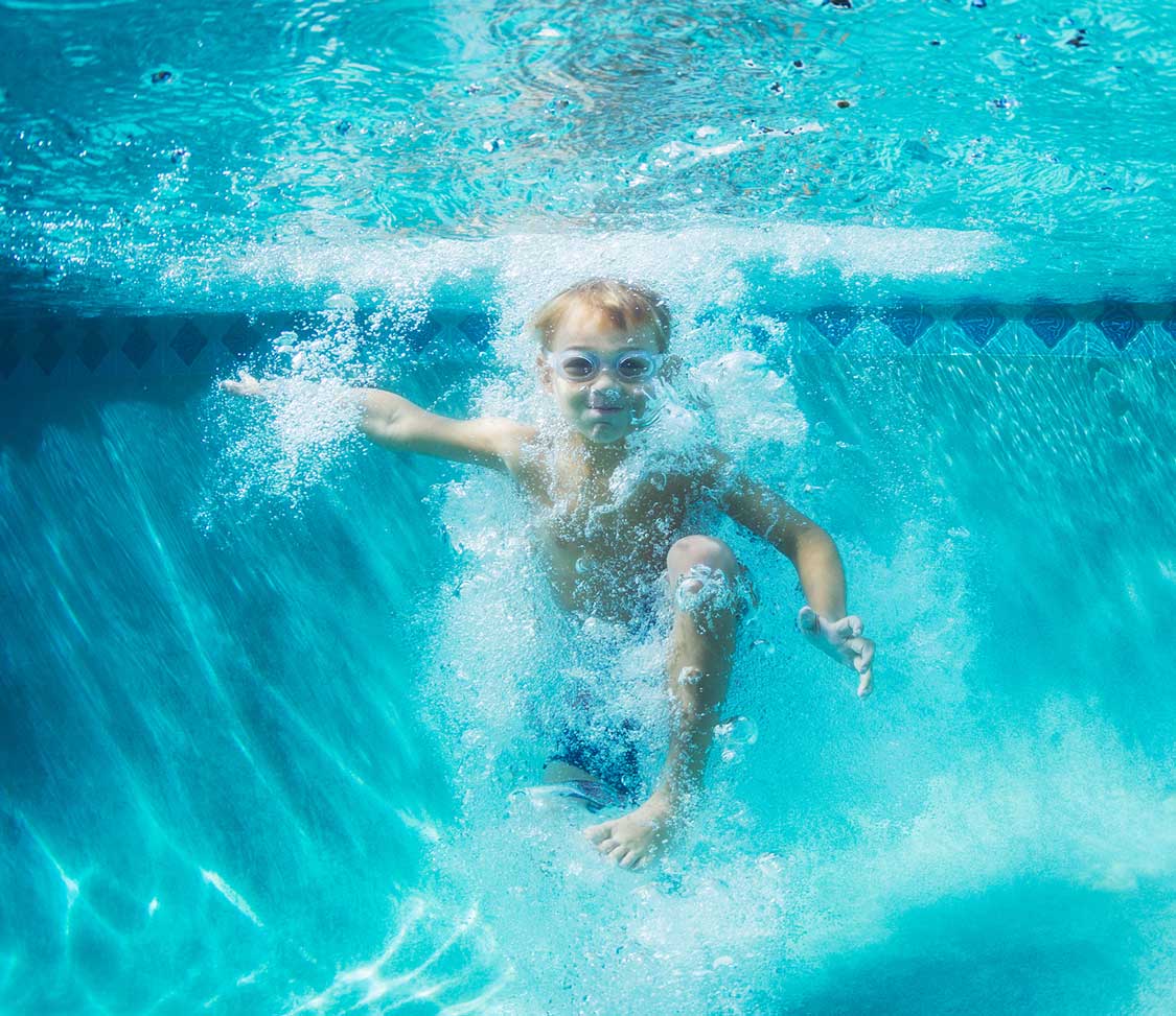 Little boy wearing goggles in the pool