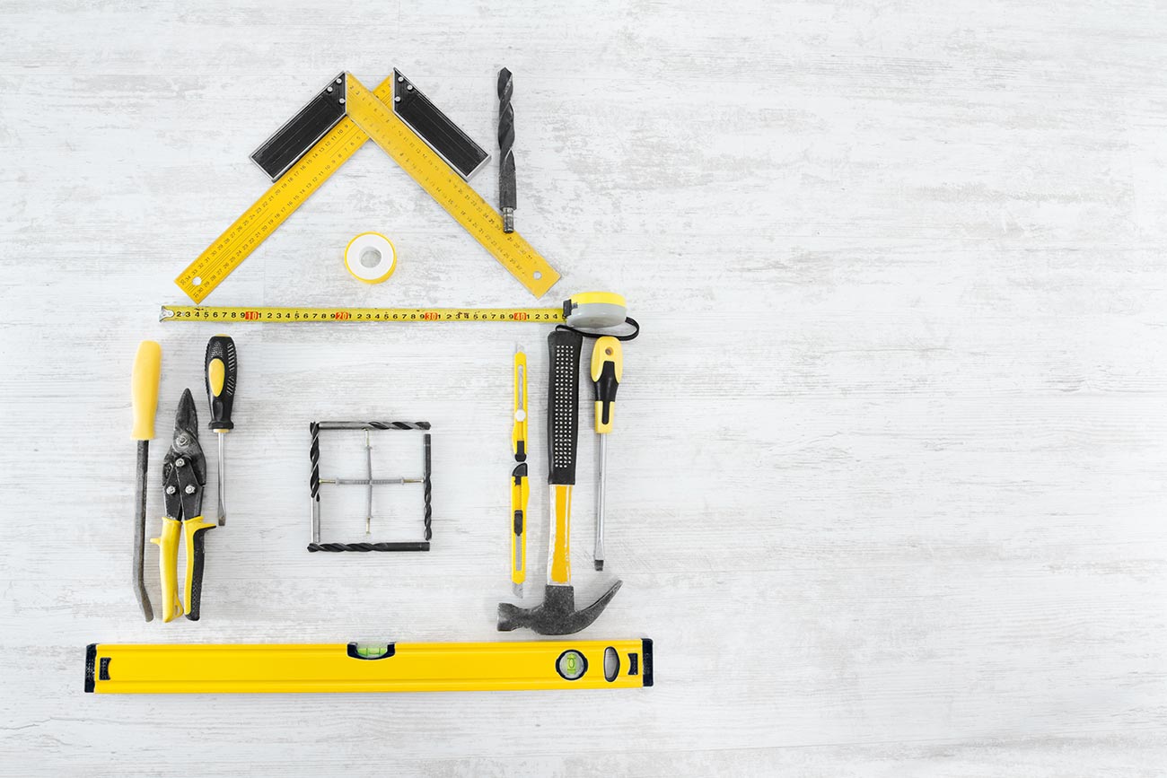 Home tools shaped into a house on a white wooden background