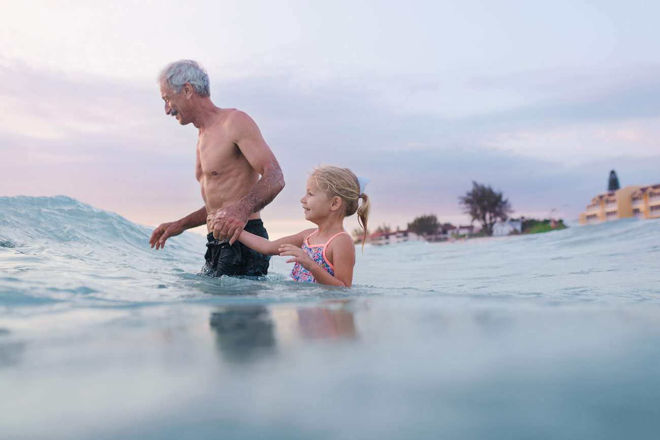 little girl and grandpa going into the ocean