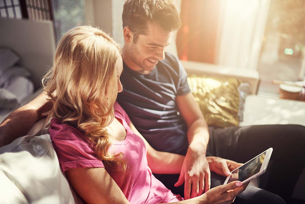 Attractive couple using tablet together on couch at home