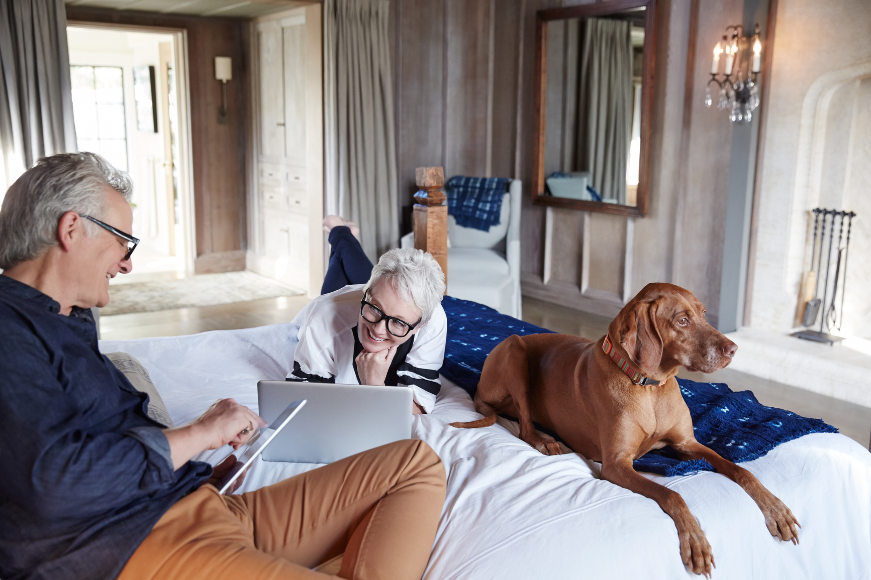 old couple in bed with dog, enjoying retirement