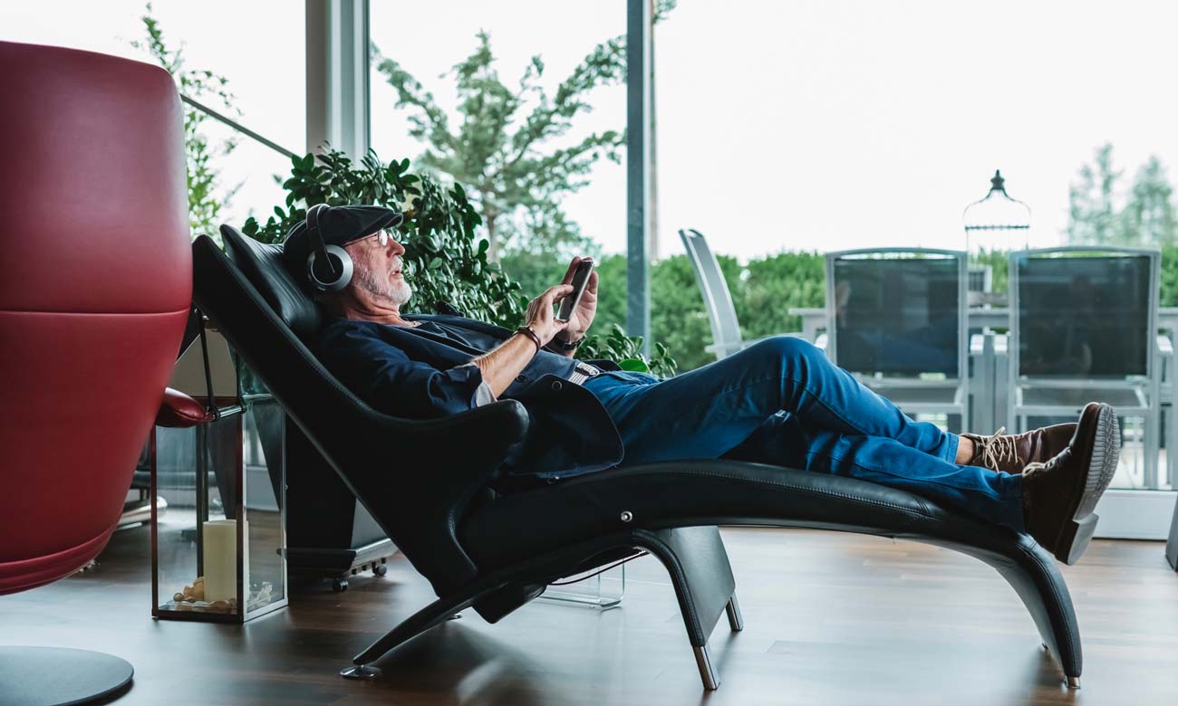 Modern senior man listening to music at home