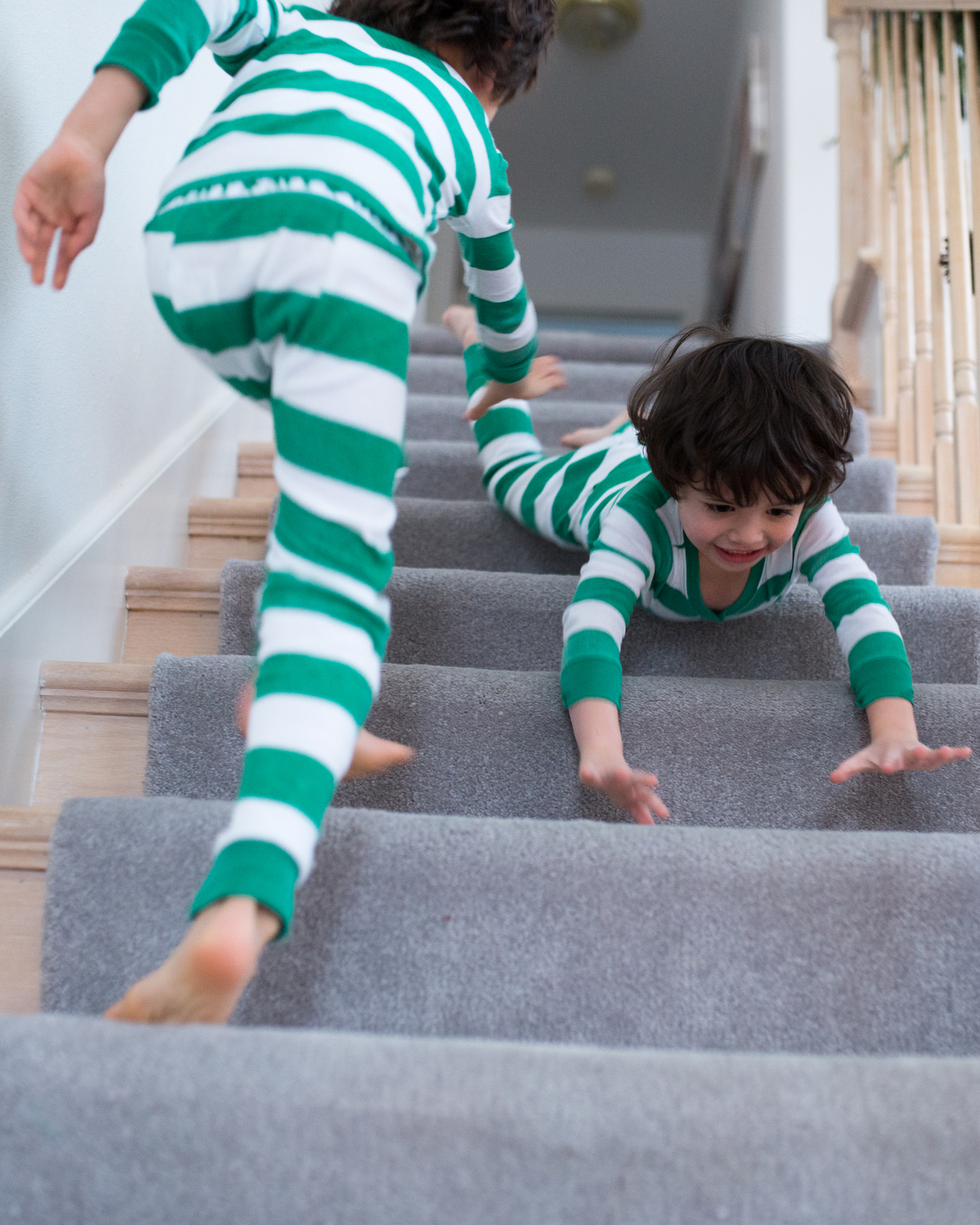 Siblings in pajamas playing by the stairs