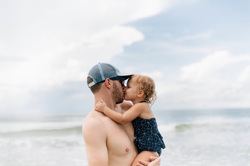 Father kissing his daughter by the beach