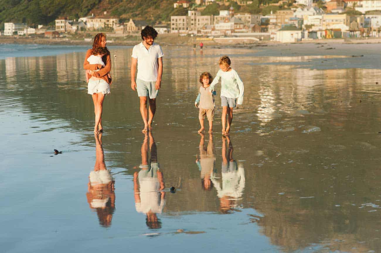 A family walks along the beach in the early morning light.