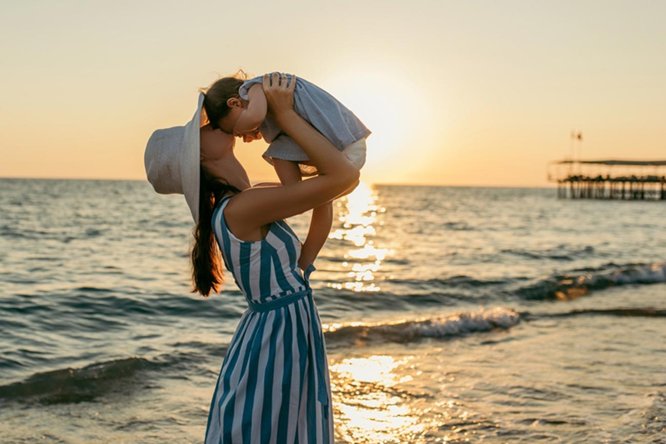 mother holding her young child in her arms at the beach