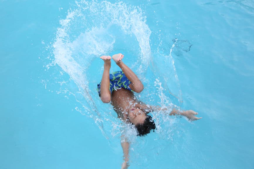 boy splashing into pool