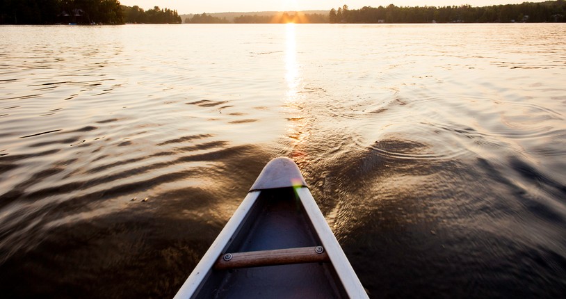 head of a small canoe along the river on a sunset