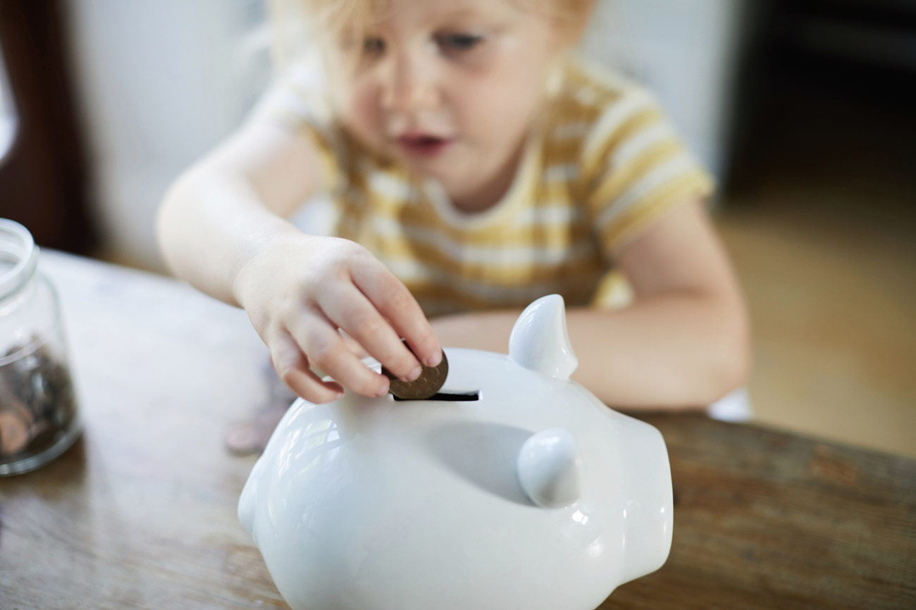 Child putting money into a piggy bank